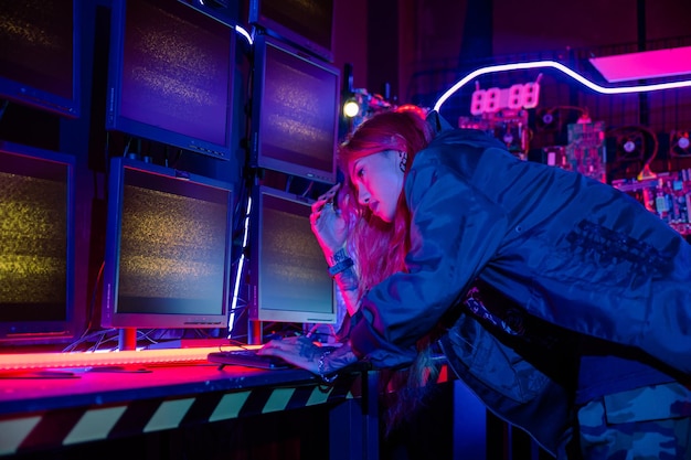asian woman wearing a black jacket hacking programming system and working with computer monitor