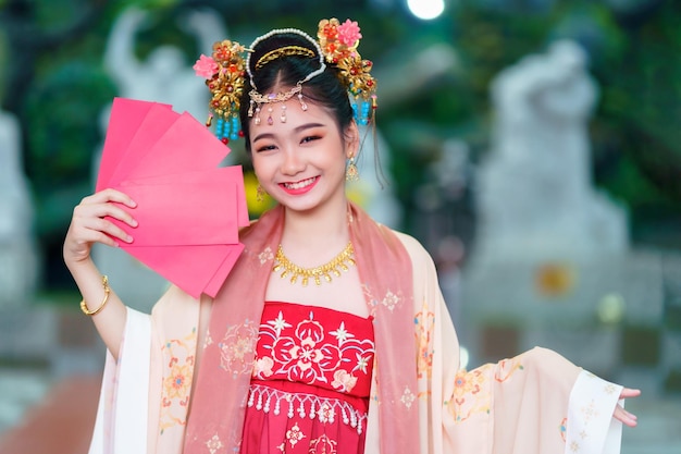 Asiatica Bambina felice che indossa costumi cinesi con in mano buste rosse decorazione per il festival del capodanno cinese celebra la cultura della Cina al santuario cinese Luoghi pubblici in Thailandia