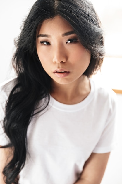 asiatica bella giovane donna in posa isolata sul muro bianco.