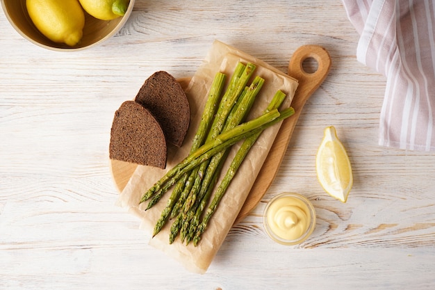 Asparagi al forno e pane nero su uno sfondo di legno, vista dall'alto.