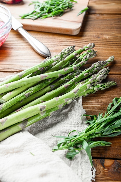 Asparagi biologici uova e condimento francese ingredienti con senape di Digione, cipolla tritata in taragone di aceto rosso su fondo in legno chiaro, vista laterale verticale.