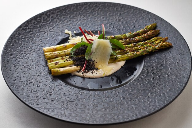 Asparagi con parmigiano su un piatto nero