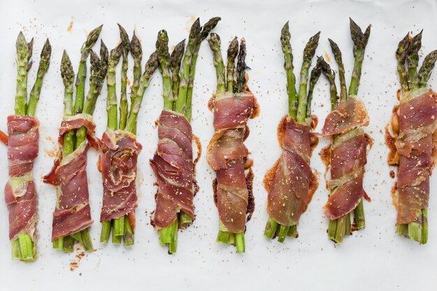 Asparagi con prosciutto su sfondo bianco