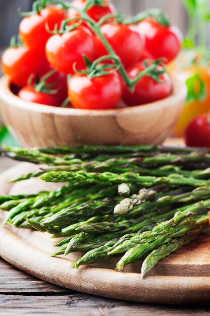 Asparagi crudi con pomodoro sul tavolo di legno