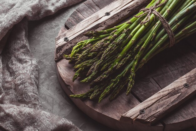 Asparagi su un tagliere. Cibo sano, salute su uno sfondo concreto.