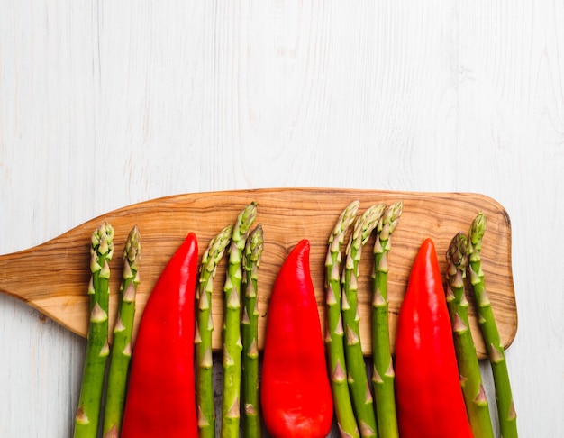 Asparagi verdi e peperoni rossi su un tagliere di legno