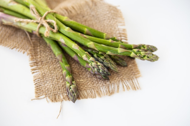 Asparagi verdi freschi legati con filo e adagiati su un sacco. Concetto di cibo sano e salutare.