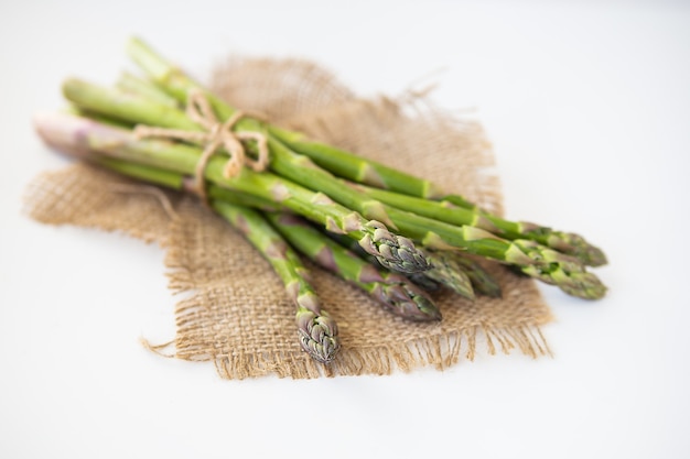 Asparagi verdi freschi legati con filo e adagiati su un sacco. Concetto di cibo sano e salutare.