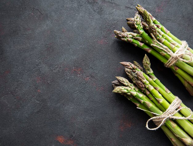 Asparagi verdi freschi su fondo di cemento nero. Lay piatto