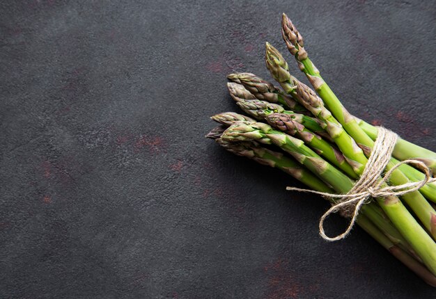 Asparagi verdi freschi sulla tavola di cemento nero. Lay piatto