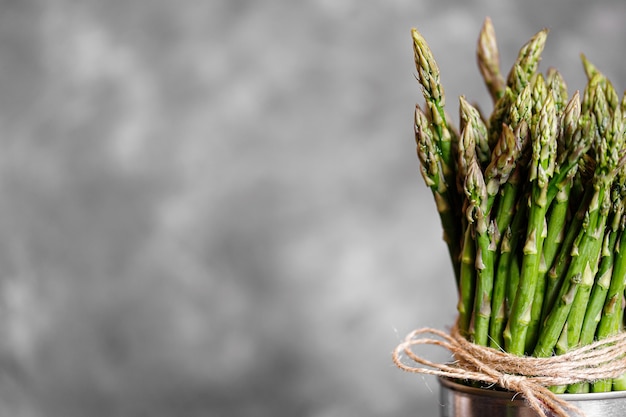 Asparago. Asparagi verdi freschi su fondo rustico grigio. Spazio di copia vista dall'alto. Mazzetti di asparagi verdi