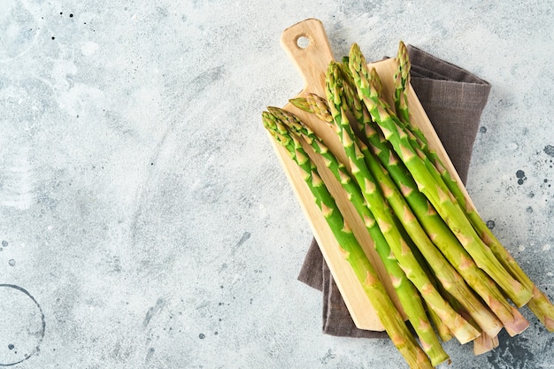 Asparago. Mazzo di asparagi verdi freschi pronto per la cottura su fondo di legno vecchio bianco. Spazio di copia vista dall'alto.