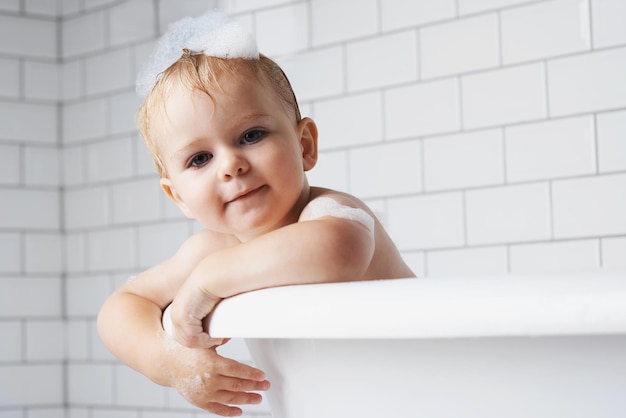 Aspettando che la mamma mi lavi Ritratto di un adorabile bambino in piedi nella vasca da bagno