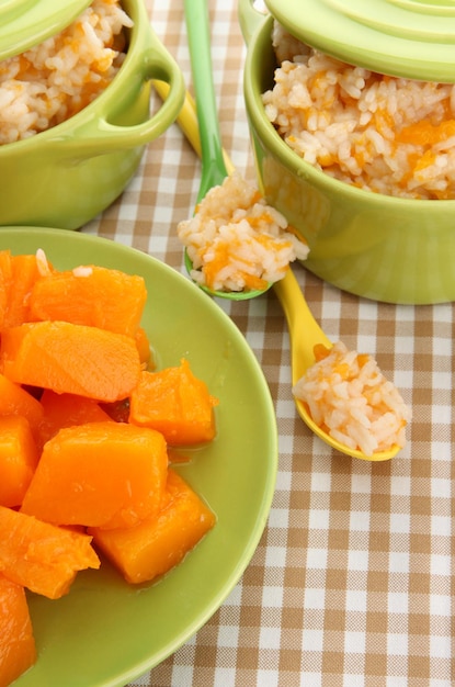 Assaggia il porridge di riso con la zucca in casseruole sullo sfondo della tovaglia