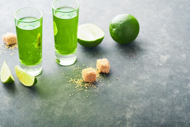 Assenzio Due bicchieri di assenzio con zucchero di canna e lime su sfondo scuro Bevanda alcolica forte Concetto di carta Bar Posto per il testo