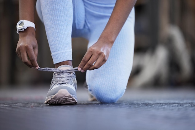 Assicurati che siano al sicuro prima di iniziare Primo piano di una donna irriconoscibile che si lega i lacci in una palestra