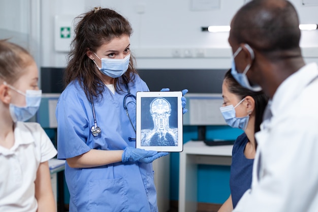 Assistente della donna del radiologo che tiene il computer tablet che mostra la radiografia del paziente