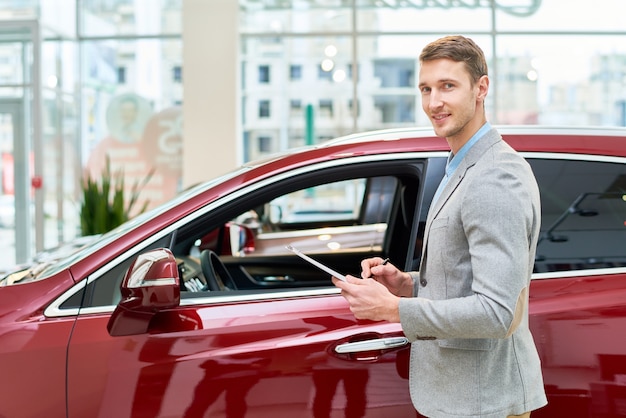 Assistente di vendite bello che presenta le automobili