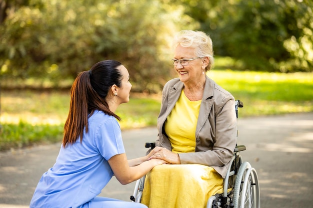Assistente infermieristico che si prende cura di una donna anziana in sedia a rotelle
