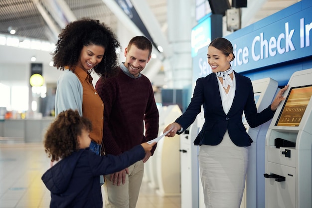 Assistente passeggeri donna e famiglia all'aeroporto presso la stazione di check-in self-service per informazioni, aiuto o domande frequenti Agente femminile amichevole felice che aiuta i viaggiatori a registrarsi o prenotare il biglietto aereo