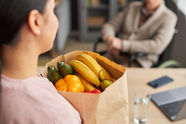 Assistente sociale che porta cibo all'uomo anziano