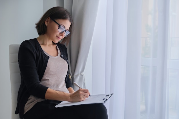 Assistente sociale, psicologo che si siede vicino alla finestra con il tagliere