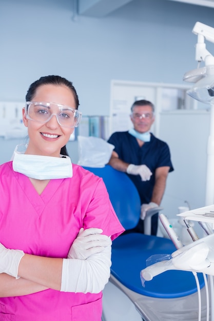 Assistente sorridente e dentista dietro di lei con occhiali protettivi