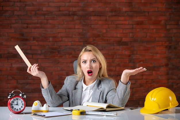 Assistente tecnico femminile di vista frontale che si siede dietro il suo posto di lavoro