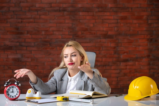 Assistente tecnico femminile di vista frontale che si siede dietro il suo posto di lavoro