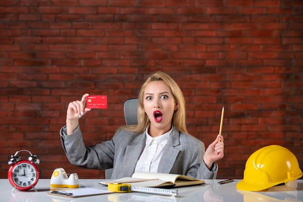 Assistente tecnico femminile di vista frontale che si siede dietro il suo posto di lavoro