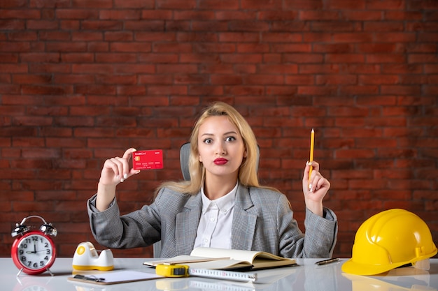 Assistente tecnico femminile di vista frontale che si siede dietro il suo posto di lavoro