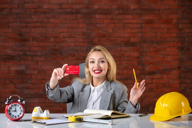 Assistente tecnico femminile di vista frontale che si siede dietro il suo posto di lavoro