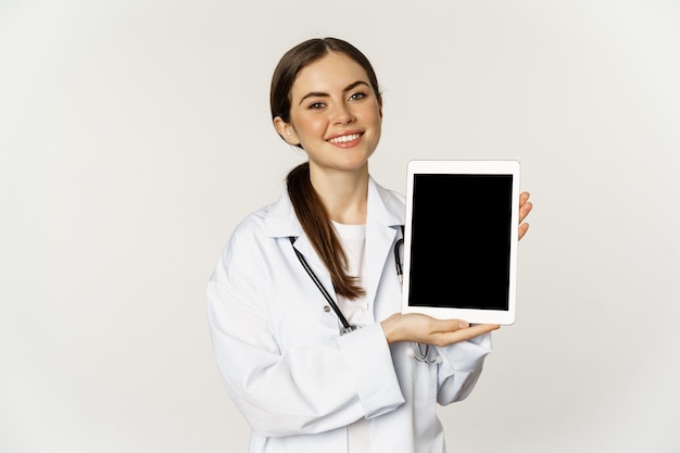 Assistenza medica online appuntamento remoto sorridente bella donna medico che mostra lo schermo del tablet digitale ...