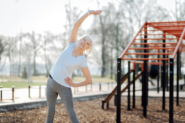 Assistenza sanitaria. Avviso donna anziana che indossa abiti sportivi e che esercitano all'aria aperta