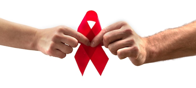 Assistenza sanitaria e concetto di medicina. Consapevolezza dell'AIDS. Le mani maschili e femminili tengono in mano un nastro rosso di sensibilizzazione sull'AIDS su uno sfondo bianco. Giornata internazionale contro l'AIDS