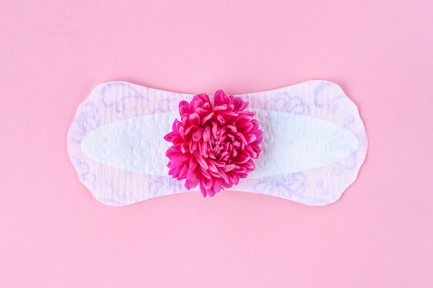 Assorbenti femminili e sanitari per giorni critici e un fiore rosa. Cura dell'igiene durante le mestruazioni. Ciclo mestruale regolare. Protezione mensile