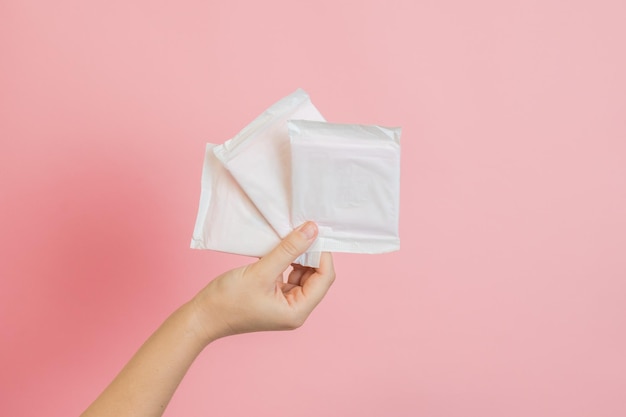 Assorbenti igienici imballati in bianco in mano Concetto di mestruazione ovulazione riproduzione dolore e igiene personale