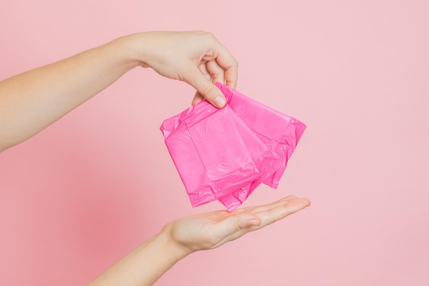 Assorbenti igienici in mano su sfondo rosa Concetto di mestruazione ovulazione riproduzione dolore e igiene personale