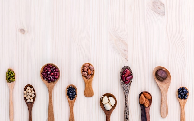 Assortimento dei fagioli e delle lenticchie in cucchiaio di legno su fondo di legno.