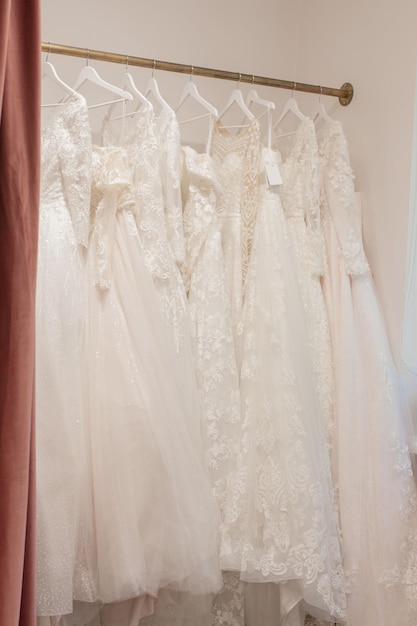 Assortimento di abiti appesi a una gruccia sullo sfondo studio Tendenze del matrimonio di moda Interno del negozio di nozze