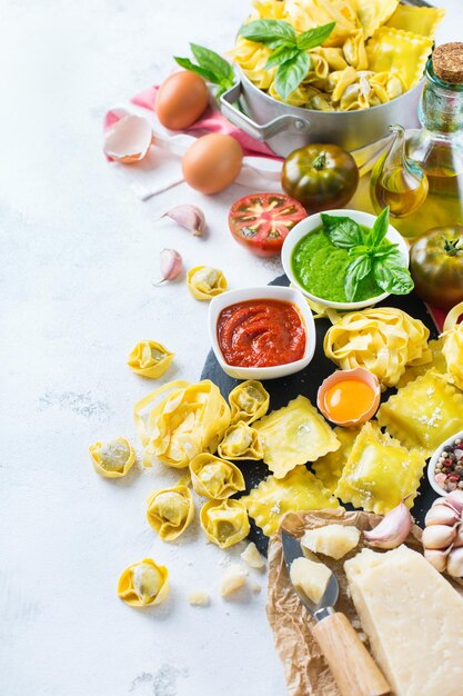 Assortimento di cibo italiano e ingredienti ravioli pasta spaghetti pesto salsa di pomodoro olio d'oliva parmigiano copia spazio sullo sfondo