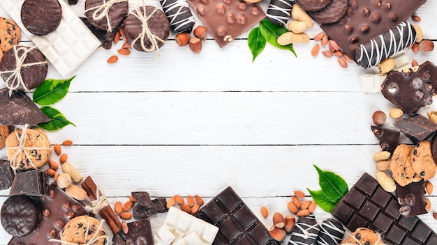 Assortimento di cioccolato con noci, biscotti e cacao su sfondo bianco in legno Vista dall'alto Copia spazio per il testo