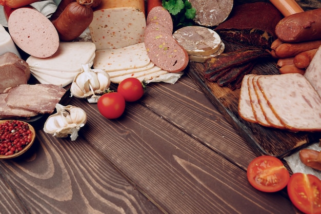 Assortimento di diverse salsicce e carne disposte su fondo di legno marrone