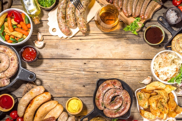 Assortimento di diverse salsicce fritte. Set con varie carni bavaresi, Francoforte, salsicce alla griglia tedesche, Oktoberfest o concetto di festa barbecue estiva, vecchio tavolo in legno sfondo spazio copia vista dall'alto