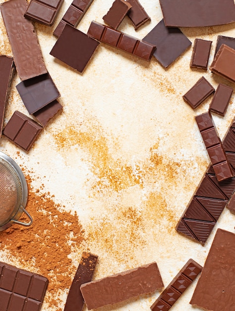 Assortimento di diversi tipi di cioccolato e cacao in polvere su uno sfondo di marmo chiaro. Vista dall'alto, piatto. Spazio per il testo