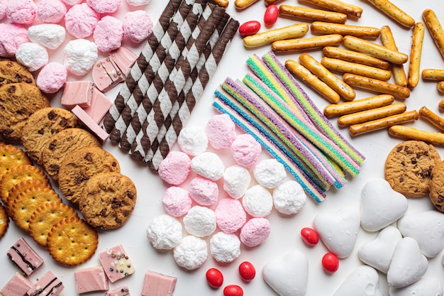 Assortimento di dolci su uno sfondo bianco. Vari dolci, biscotti, cioccolato, marshmallow, vista dall'alto.