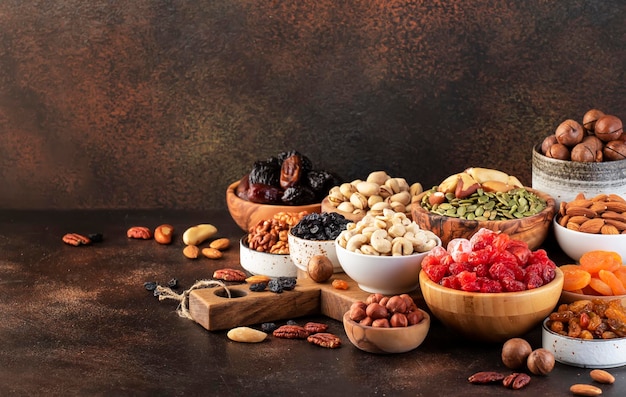 Assortimento di frutta secca e noci Spuntini sani Albicocche secche fichi uvetta noci pecan noci nocciole mandorle e altro Sfondo tavolo marrone