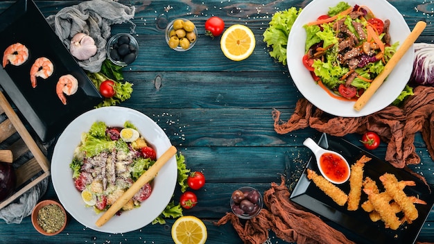 Assortimento di insalate di cibo con gamberi e carne su sfondo di legno Vista dall'alto Copia spazio per il testo