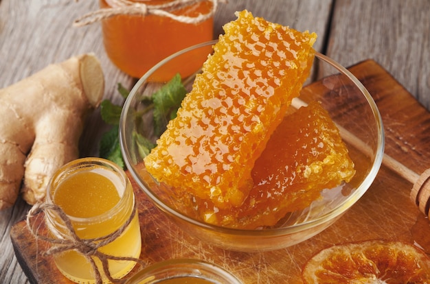 Assortimento di miele, primo piano. Composizione con vasetti di vetro pieni, favi, ciotola di polline, noci e arance secche. Sfondo dolce, carta da parati