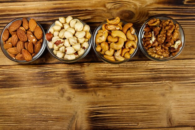 Assortimento di noci su tavola di legno Mandorla nocciola noce e anacardi in ciotole di vetro Vista dall'alto spazio copia Concetto di mangiare sano